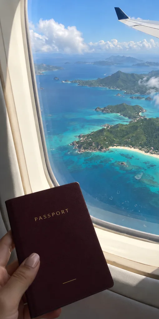 Un passeport tenu devant le hublot, au-dessus d'îles turquoise